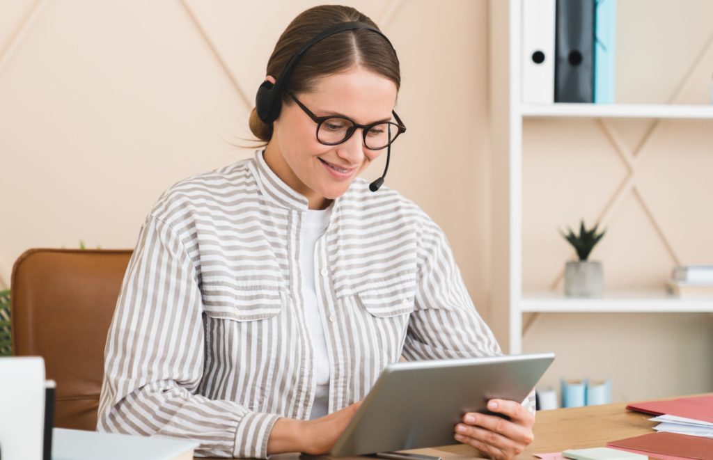 Hotline worker interpreter assistant in headset using tablet for remote work, e-commerce, e-banking