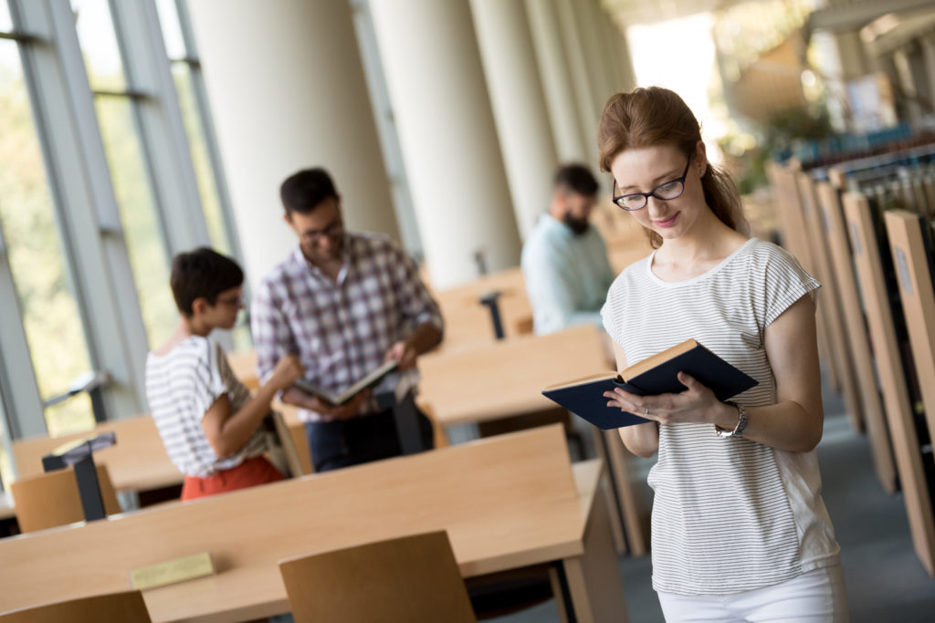 Female student reading a book at library