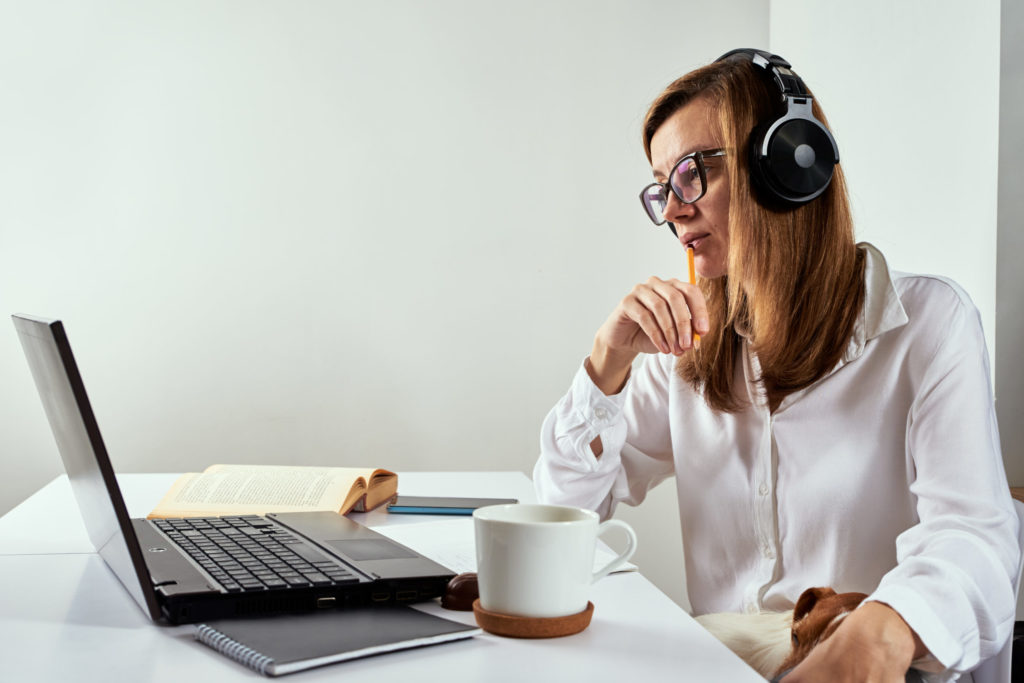 Remote work. Online cources, distance education and e-learning concept. Woman in headphones listen audio course at laptop